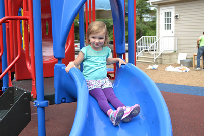A little girl on a blue sliding board.