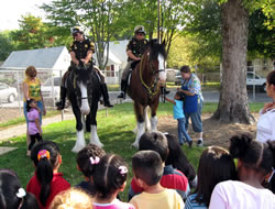 Police officers on their horses speaking to a group of Head Start students