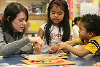 Photo of teacher working on a puzzle with two students.