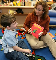 Photo of woman showing a book to a young boy